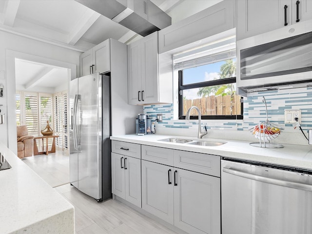 kitchen featuring a sink, stainless steel appliances, beamed ceiling, and decorative backsplash