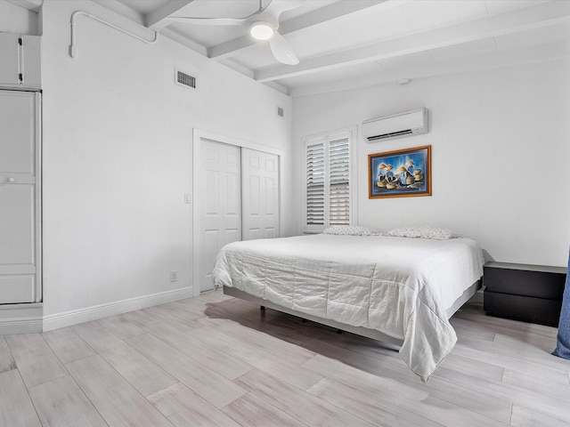 bedroom with a closet, a wall unit AC, visible vents, beamed ceiling, and light wood-style floors