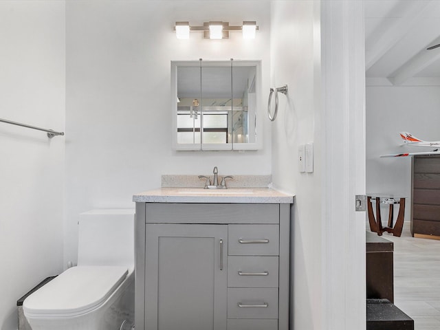 bathroom with toilet, wood finished floors, and vanity