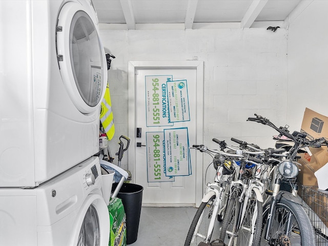 laundry room with stacked washer and clothes dryer, laundry area, and concrete block wall