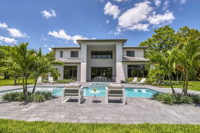 back of property featuring a patio area, an in ground hot tub, stucco siding, and an outdoor pool