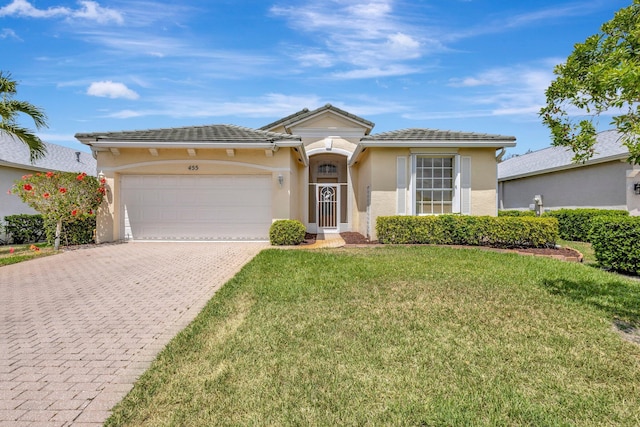 view of front of property featuring decorative driveway, a garage, stucco siding, a tile roof, and a front yard