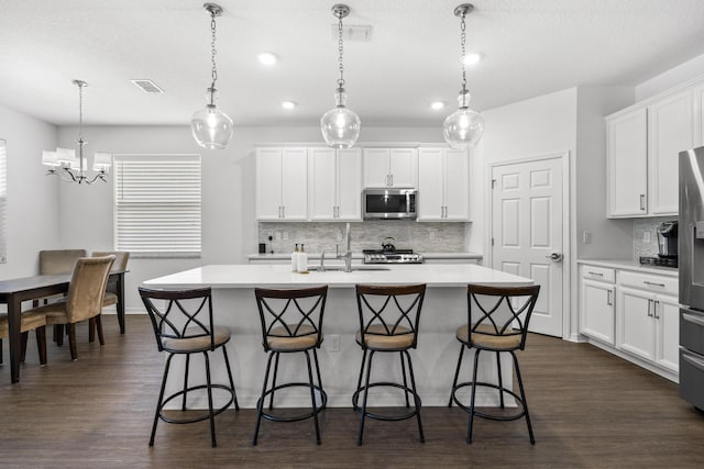 kitchen with appliances with stainless steel finishes, light countertops, backsplash, a kitchen bar, and recessed lighting