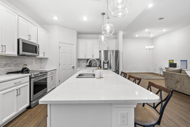 kitchen with appliances with stainless steel finishes, a sink, a kitchen breakfast bar, dark wood finished floors, and backsplash
