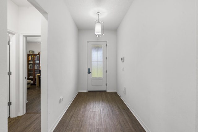 doorway to outside with dark wood-type flooring and baseboards