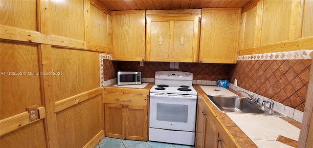 17 Brighton A 17, Boca Raton, FL 33434 - kitchen featuring white range with electric stovetop, stainless steel microwave, a sink, light tile patterned floors, and decorative backsplash