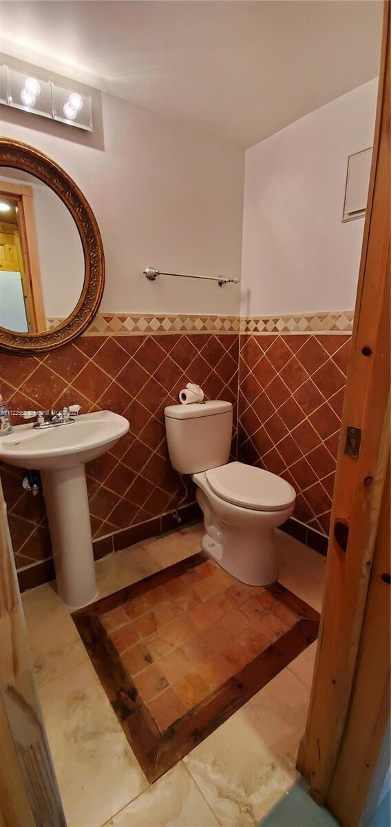 17 Brighton A 17, Boca Raton, FL 33434 - half bath with tile walls, toilet, a wainscoted wall, and a sink