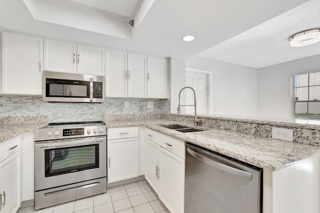 kitchen featuring appliances with stainless steel finishes, a sink, a peninsula, white cabinetry, and recessed lighting