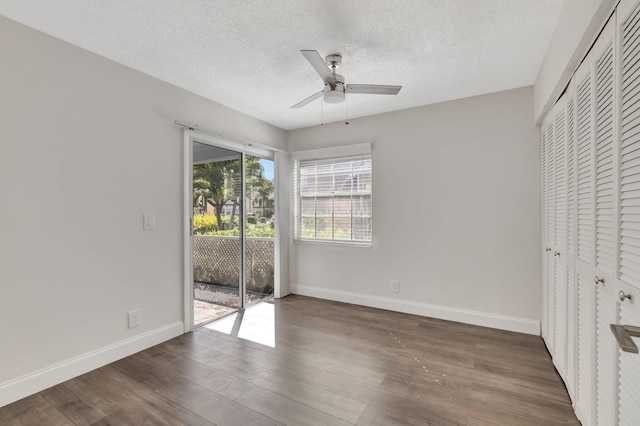 unfurnished bedroom with access to exterior, baseboards, wood finished floors, a textured ceiling, and a closet