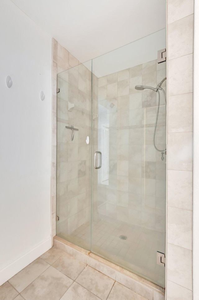 bathroom featuring tile patterned floors, a shower stall, and baseboards