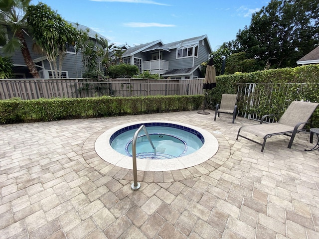 view of pool featuring fence, a community hot tub, and a patio
