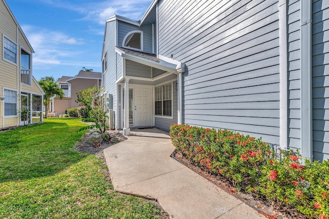 view of exterior entry featuring a lawn