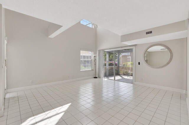 unfurnished room with baseboards, light tile patterned floors, and high vaulted ceiling