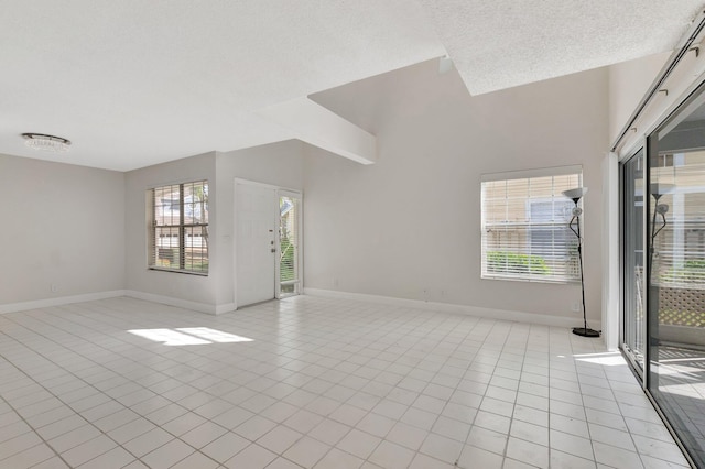unfurnished living room featuring baseboards, light tile patterned flooring, and a textured ceiling