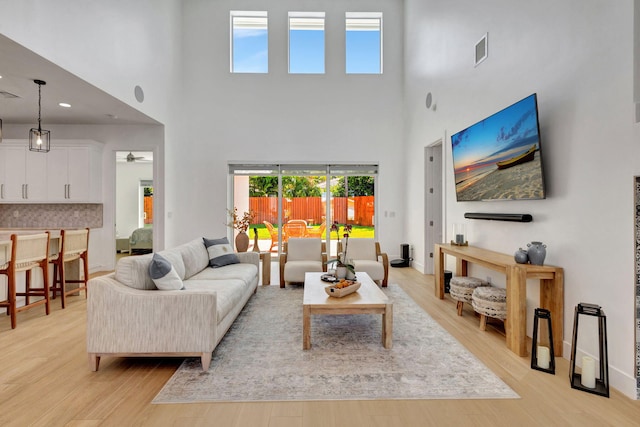 12952 Drayton Rd, North Palm Beach, FL 33408 - living room featuring light wood-style floors, a healthy amount of sunlight, visible vents, and a towering ceiling