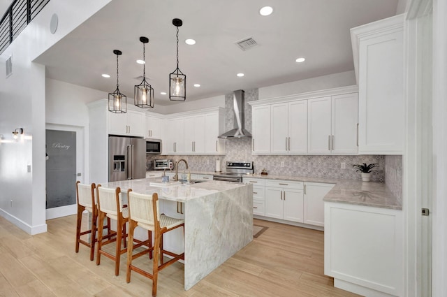 12952 Drayton Rd, North Palm Beach, FL 33408 - kitchen with light wood-style flooring, wall chimney exhaust hood, white cabinetry, appliances with stainless steel finishes, and tasteful backsplash