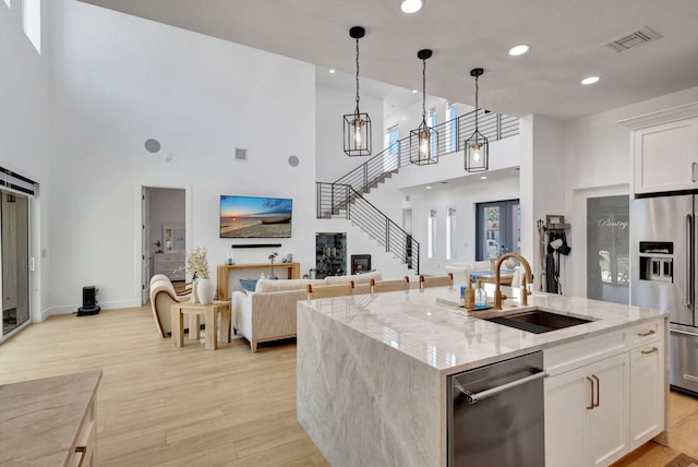12952 Drayton Rd, North Palm Beach, FL 33408 - kitchen featuring light wood finished floors, visible vents, a sink, a towering ceiling, and stainless steel appliances