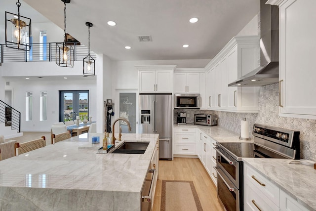 12952 Drayton Rd, North Palm Beach, FL 33408 - kitchen featuring light wood finished floors, visible vents, a sink, wall chimney range hood, and stainless steel appliances