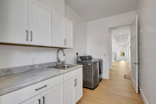 12952 Drayton Rd, North Palm Beach, FL 33408 - clothes washing area featuring a sink, cabinet space, separate washer and dryer, baseboards, and light wood-style floors
