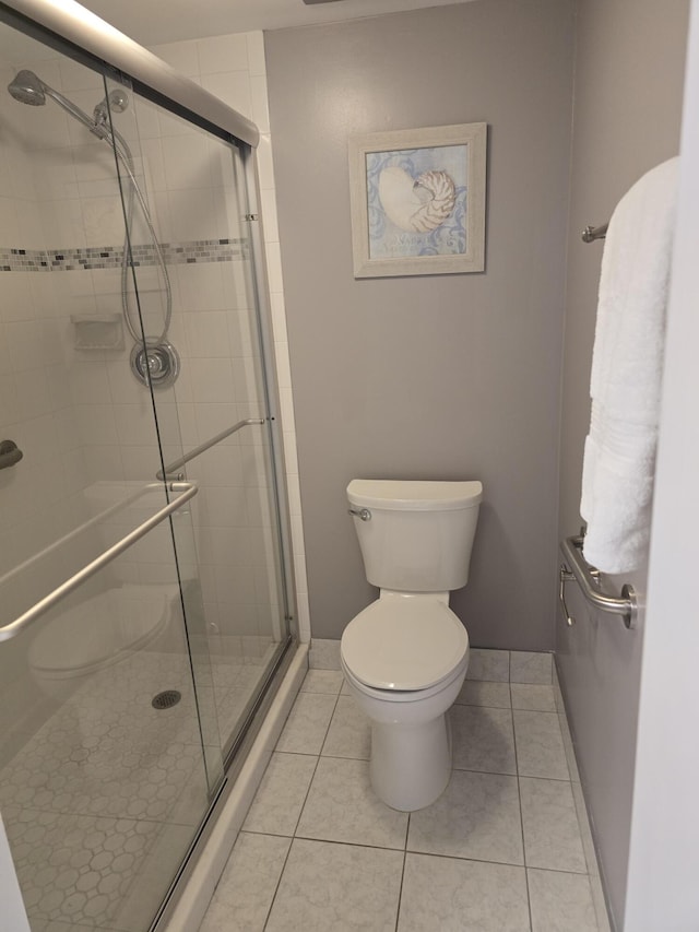full bathroom featuring a stall shower, tile patterned flooring, toilet, and baseboards