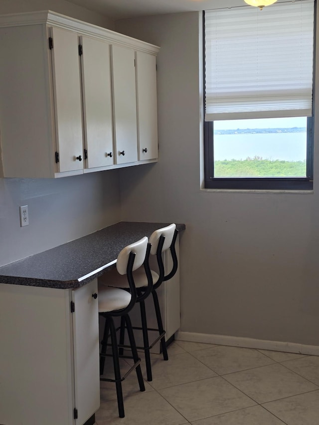 kitchen with white cabinetry, baseboards, dark countertops, and light tile patterned floors