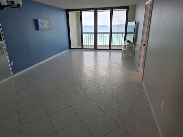empty room featuring baseboards, tile patterned flooring, and expansive windows