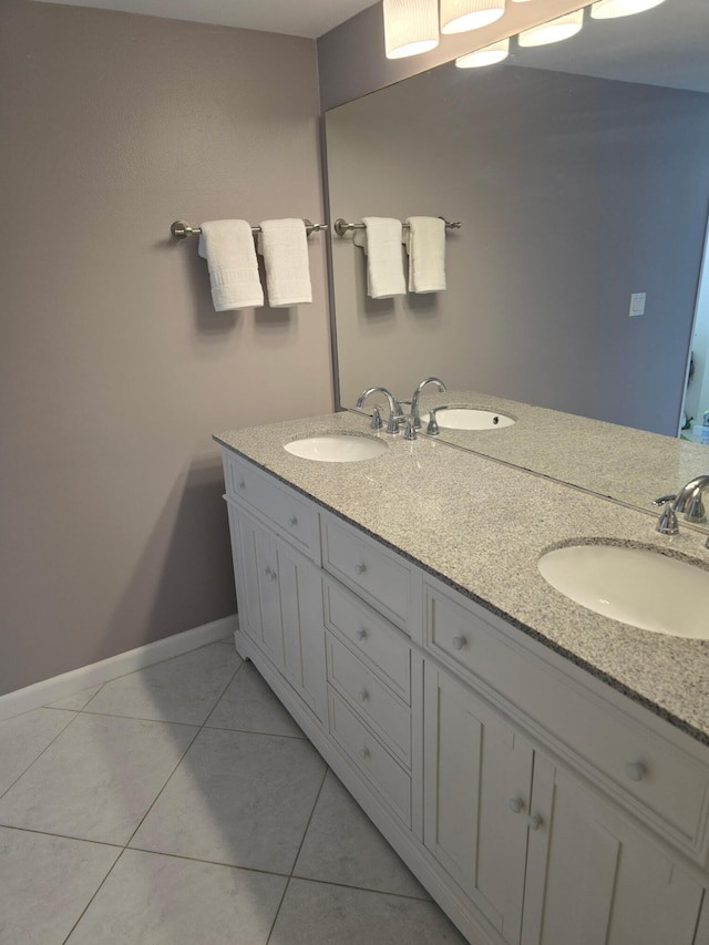 full bathroom with baseboards, tile patterned flooring, double vanity, and a sink
