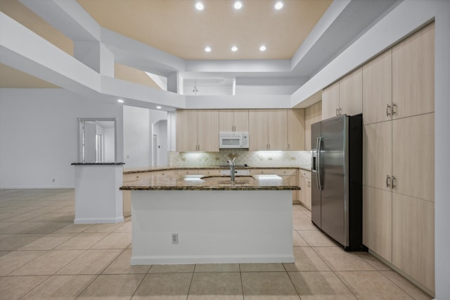 4065 Manchester Lake Dr, Lake Worth, FL 33449 - kitchen with stainless steel refrigerator with ice dispenser, white microwave, dark stone counters, light brown cabinetry, and light tile patterned flooring