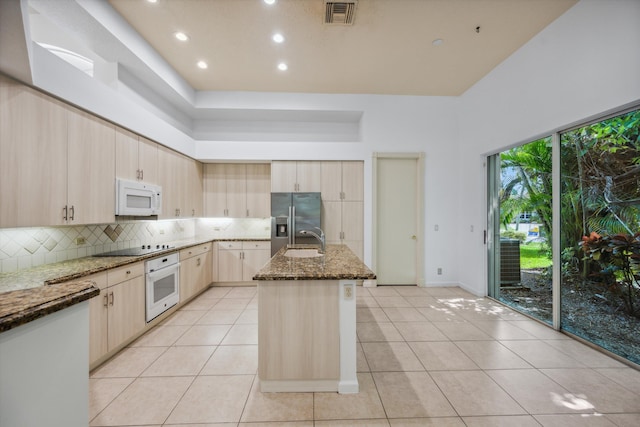4065 Manchester Lake Dr, Lake Worth, FL 33449 - kitchen featuring white appliances, dark stone countertops, backsplash, a sink, and light brown cabinets