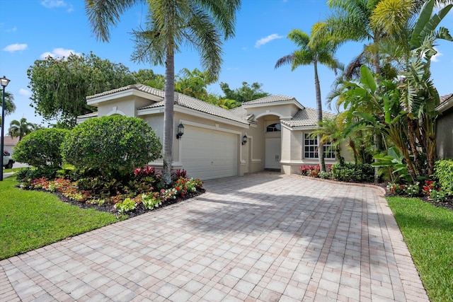 4065 Manchester Lake Dr, Lake Worth, FL 33449 - mediterranean / spanish-style house featuring stucco siding, a garage, decorative driveway, and a tiled roof