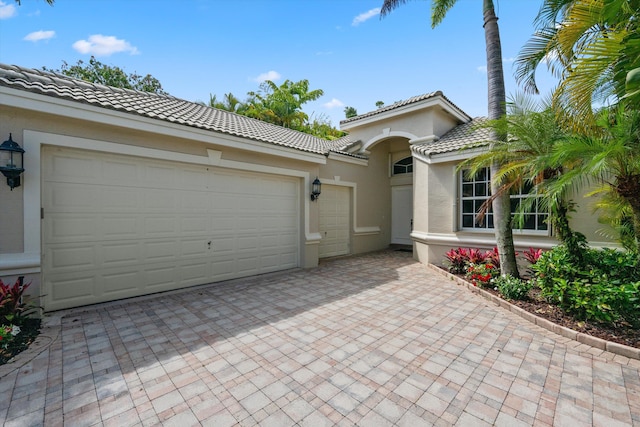 4065 Manchester Lake Dr, Lake Worth, FL 33449 - mediterranean / spanish-style home featuring decorative driveway, a tiled roof, stucco siding, and an attached garage