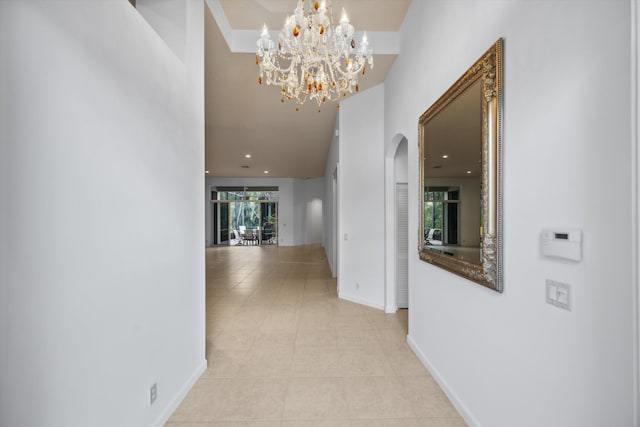 4065 Manchester Lake Dr, Lake Worth, FL 33449 - hall featuring arched walkways, a high ceiling, tile patterned floors, a chandelier, and baseboards