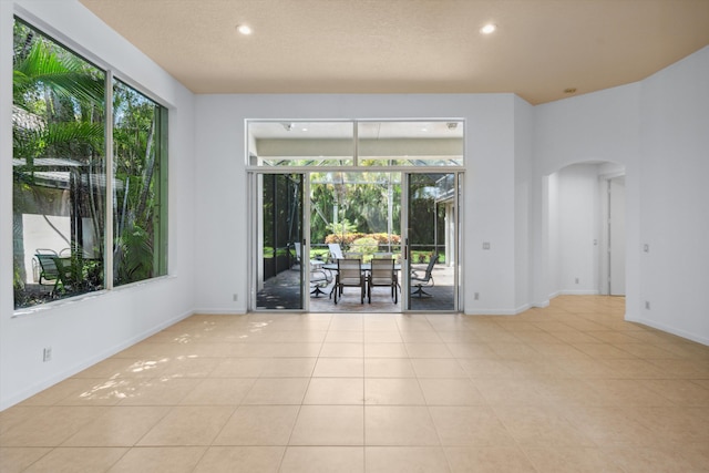 4065 Manchester Lake Dr, Lake Worth, FL 33449 - tiled empty room featuring arched walkways, recessed lighting, and baseboards