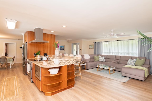 kitchen with appliances with stainless steel finishes, brown cabinets, open shelves, wall chimney range hood, and light wood-type flooring