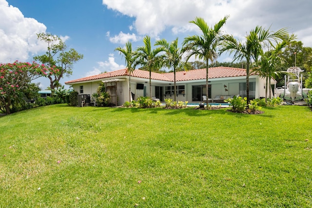 back of property with a tile roof, stucco siding, a yard, and an outdoor pool