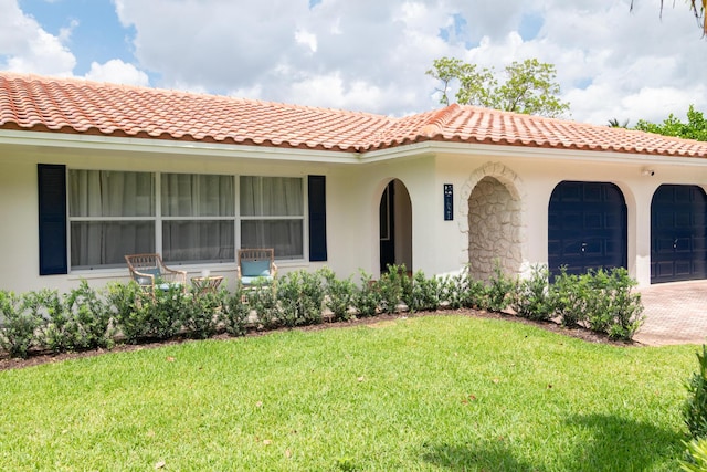 mediterranean / spanish house featuring a front yard, stucco siding, a tiled roof, and a garage