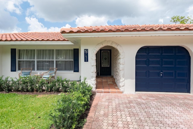 view of front of property featuring stucco siding, a tiled roof, a garage, and decorative driveway
