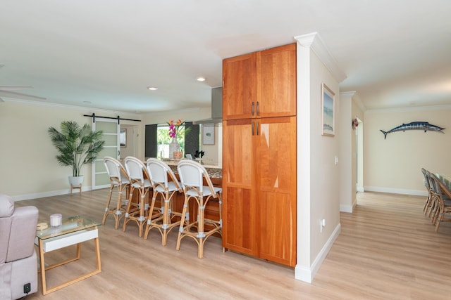 kitchen featuring a barn door, light wood-type flooring, recessed lighting, crown molding, and baseboards