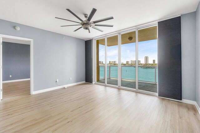 2640 Lake Shore Dr Unit 614, Riviera Beach, FL 33404 - empty room featuring a wall of windows, wood finished floors, a ceiling fan, baseboards, and a water view
