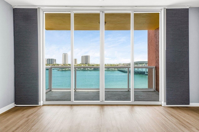 2640 Lake Shore Dr Unit 614, Riviera Beach, FL 33404 - doorway with a wall of windows, wood finished floors, a water view, and baseboards