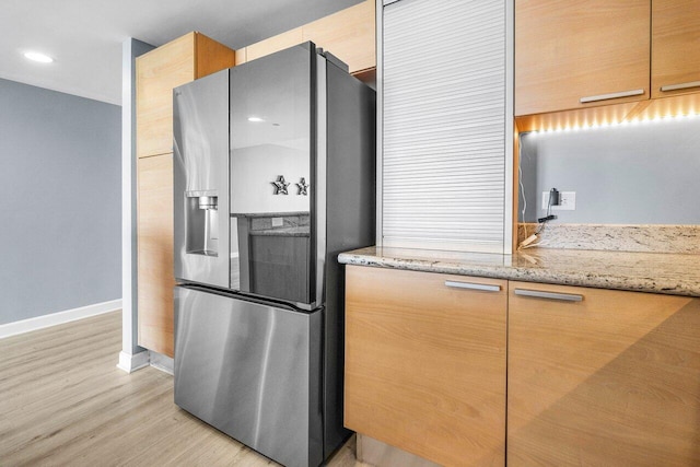 2640 Lake Shore Dr Unit 614, Riviera Beach, FL 33404 - kitchen with stainless steel fridge with ice dispenser, baseboards, light wood-style flooring, and light stone countertops