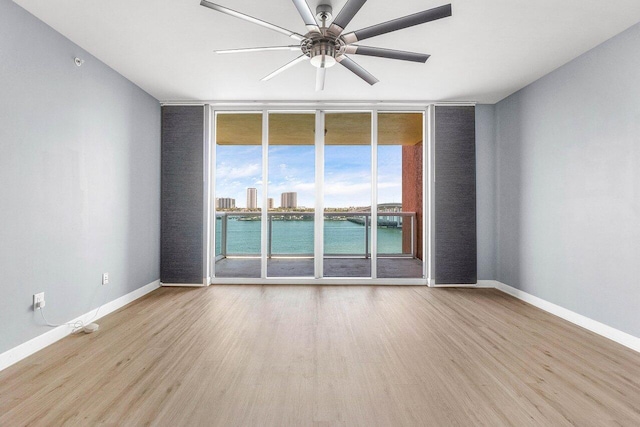 2640 Lake Shore Dr Unit 614, Riviera Beach, FL 33404 - unfurnished room featuring a wall of windows, wood finished floors, a ceiling fan, baseboards, and a water view