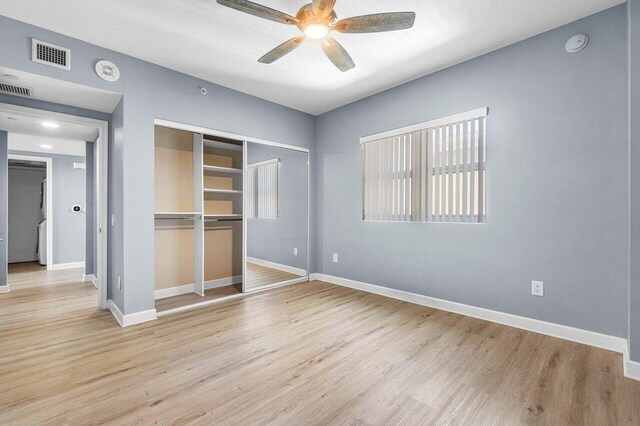 2640 Lake Shore Dr Unit 614, Riviera Beach, FL 33404 - unfurnished bedroom featuring a closet, baseboards, multiple windows, and wood finished floors