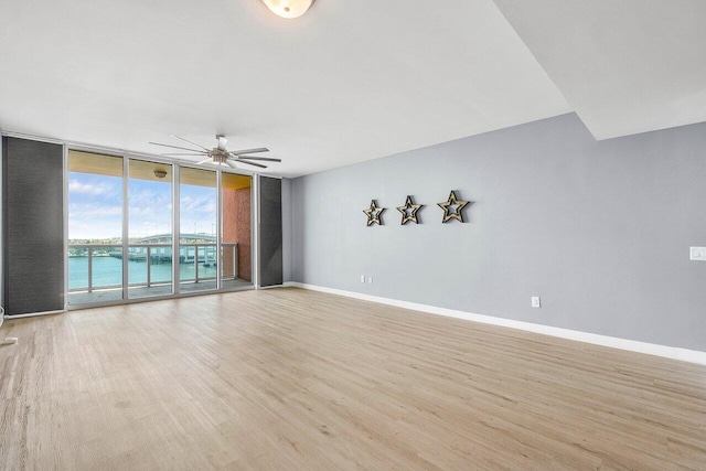 2640 Lake Shore Dr Unit 614, Riviera Beach, FL 33404 - unfurnished room featuring floor to ceiling windows, a ceiling fan, light wood-style floors, baseboards, and a water view