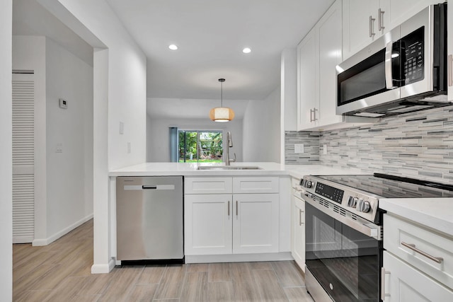 kitchen featuring appliances with stainless steel finishes, a sink, decorative backsplash, recessed lighting, and light countertops