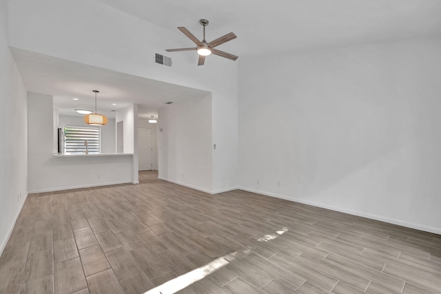unfurnished living room featuring wood tiled floors, ceiling fan, and baseboards