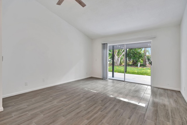 unfurnished room featuring vaulted ceiling, wood finished floors, a ceiling fan, and baseboards