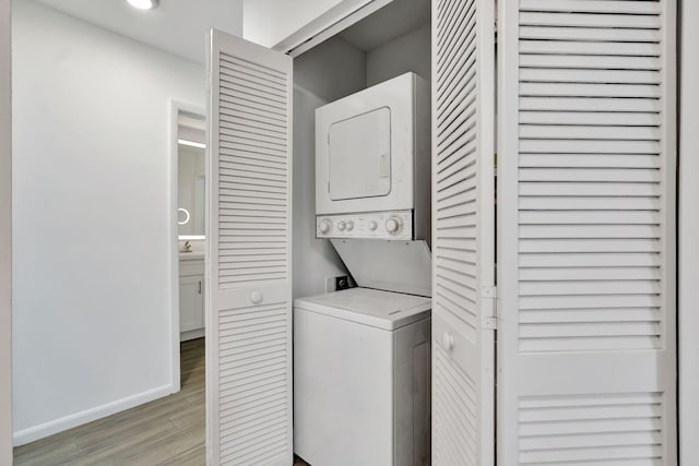 washroom with stacked washer / drying machine, light wood-style flooring, baseboards, and recessed lighting
