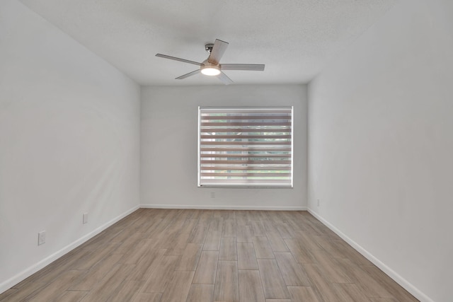 empty room with ceiling fan, wood finished floors, and baseboards