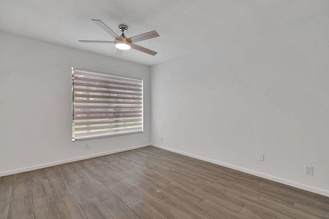 unfurnished room featuring ceiling fan, wood finished floors, and baseboards